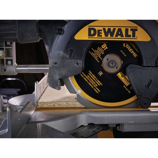 Close-up of a DEWALT circular saw cutting a piece of wood on a workbench.