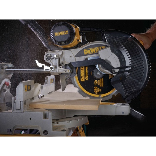 A close-up view of a DEWALT miter saw cutting a piece of wood, with visible sawdust and the DEWALT logo on the saw.