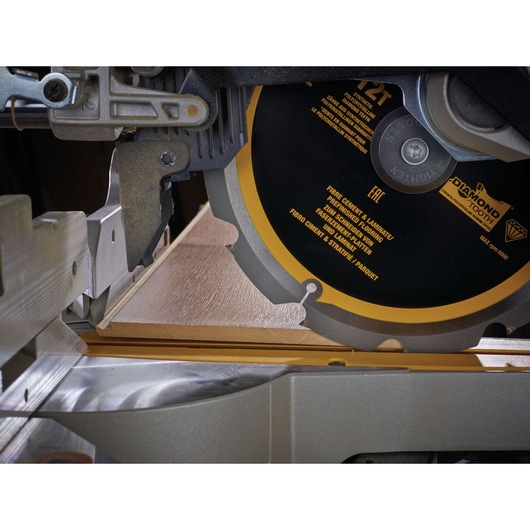 Close-up of a DEWALT saw blade cutting a piece of laminate flooring on a saw table.