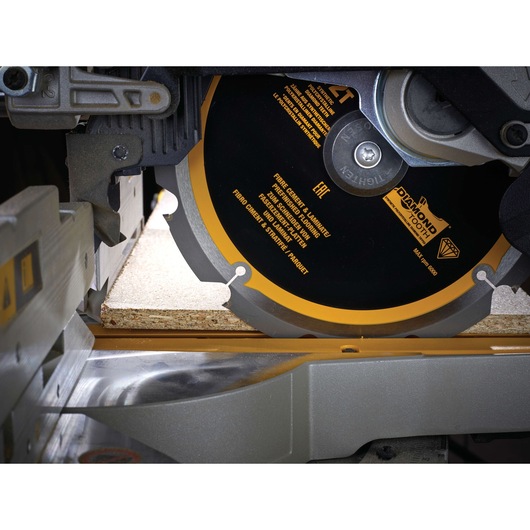 Close-up of a DEWALT saw blade cutting through a piece of laminate wood on a table saw.