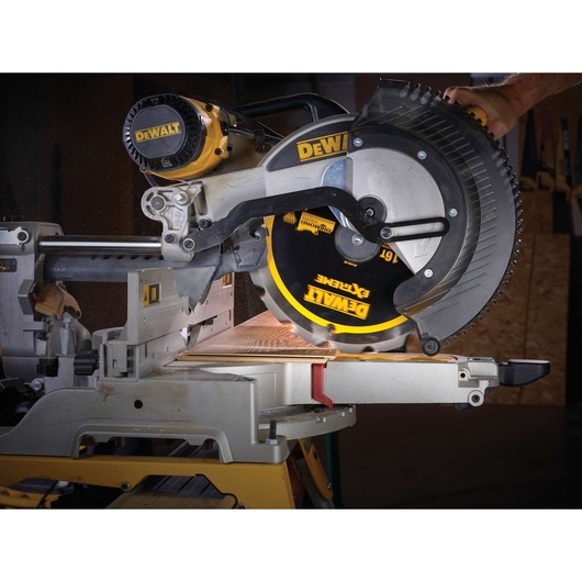 A DEWALT circular saw in use, cutting a piece of wood on a workbench. The saw blade is clearly visible with DEWALT branding