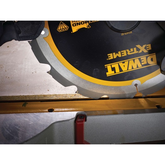 Close-up of a DEWALT Extreme saw blade cutting wood on a workbench.