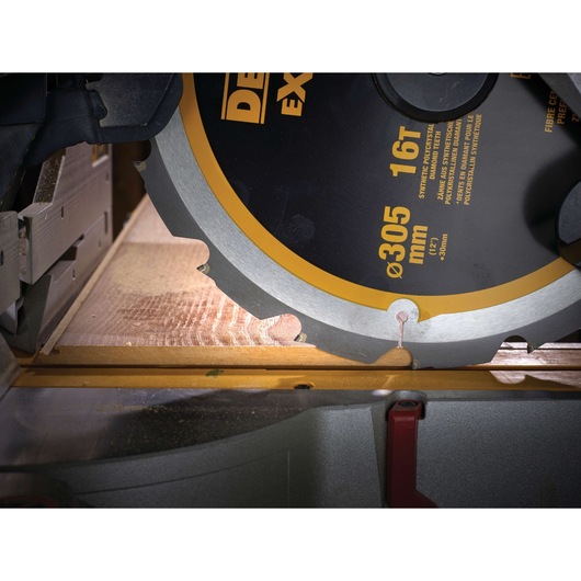 Close-up of DEWALT circular saw cutting wood, showing blade details and measurement markings.