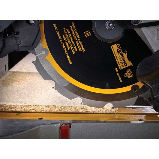 Close-up of a DEWALT DT1475 circular saw blade cutting through a wooden board in a workshop.