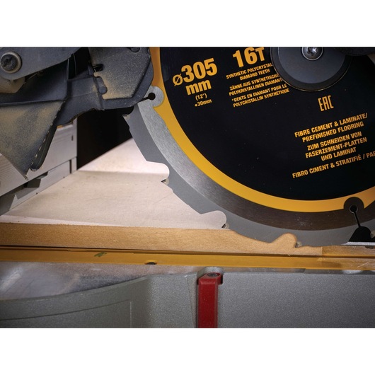 Close-up of a DEWALT circular saw blade cutting through a piece of wood, showing blade details and safety guard.