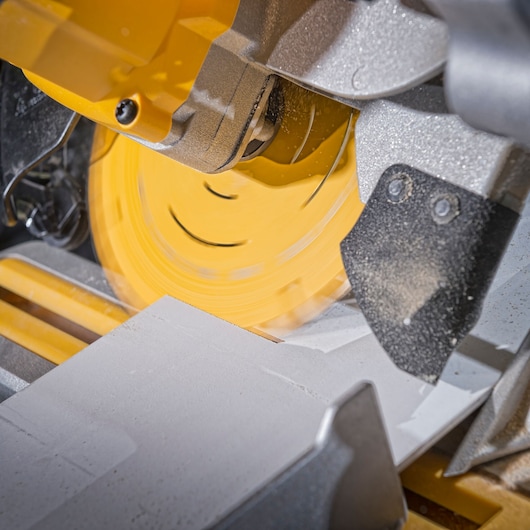 Close-up of a DEWALT circular saw cutting through a piece of material, with dust visible around the yellow rotating blade.