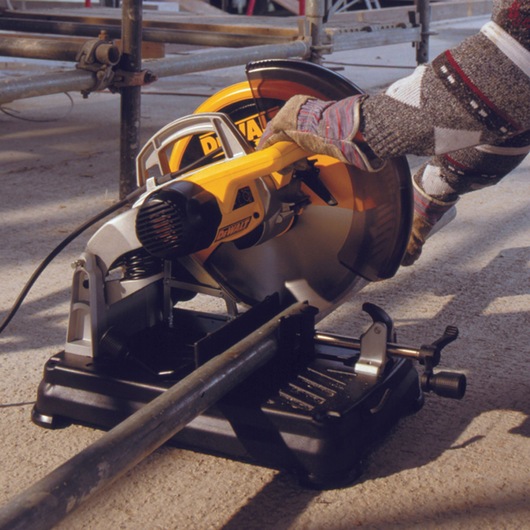 Person uses a DEWALT DT1921 saw to cut metal pipe outdoors, wearing gloves for safety.