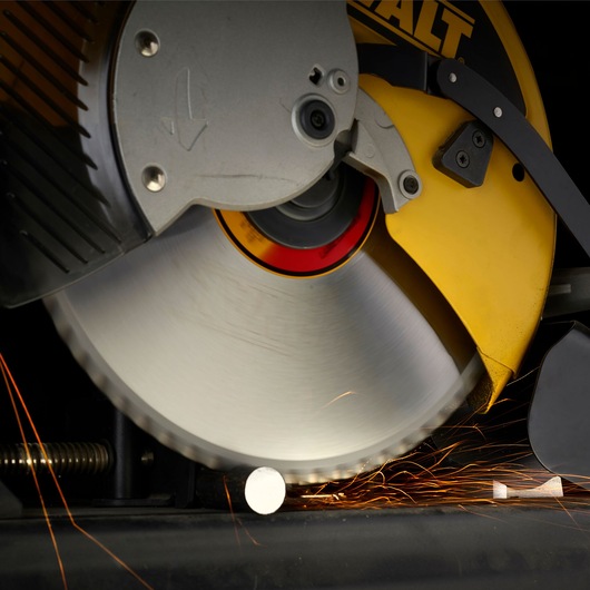 Close-up of a DEWALT circular saw blade cutting through a metal rod, with visible sparks flying from the cutting area.
