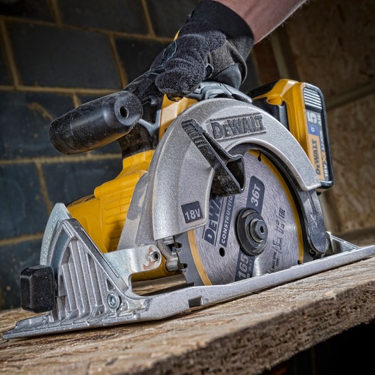 A close-up of a DEWALT cordless circular saw, model DT1950, being used to cut wood. The saw is yellow and silver with a