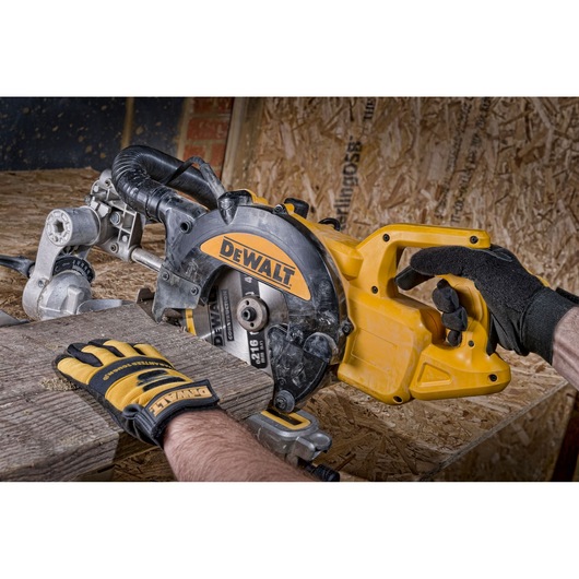 Person wearing gloves uses a DEWALT circular saw to cut a wooden plank on a workbench.