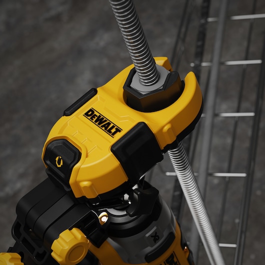 Close-up of a DEWALT tool, showing a yellow and black device securely gripping a threaded metal rod.