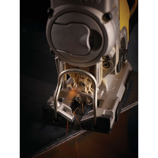 Close-up view of a DEWALT jigsaw cutting through a metal sheet, with sparks visible near the blades.