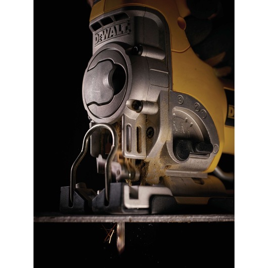 Close-up of a DEWALT jigsaw power tool in use, showing the front and side detailing, blade, and some sparks during operation.