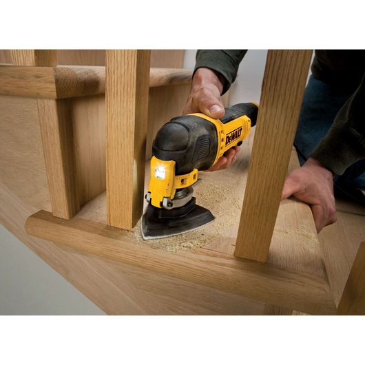 DEWALT DT3094 sander used on wooden stairs, sanding surface between railings with visible sawdust.