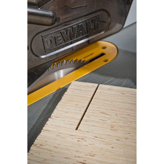 Close-up of DEWALT saw blade cutting a piece of wood, showing precision and safety guard.