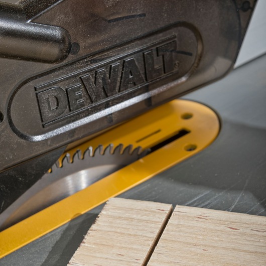 Close-up of a DEWALT saw cutting wooden pieces, showing the blade and yellow table surface.