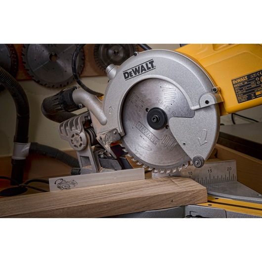 Close-up view of a DEWALT DT4323 circular saw in operation, cutting a piece of wood in a workshop setting. The saw is