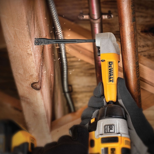 DEWALT DT4768 drill in use on wood, creating sparks, held by gloved hands, close to copper pipes.