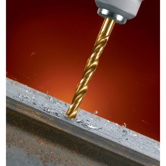 Close-up of a gold-colored drill bit drilling into a piece of metal, with metal shavings and sparks visible.