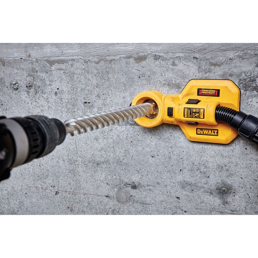 A DEWALT DT60844 yellow dust extraction attachment is shown in use with a drill and spiral drill bit on a concrete wall. The