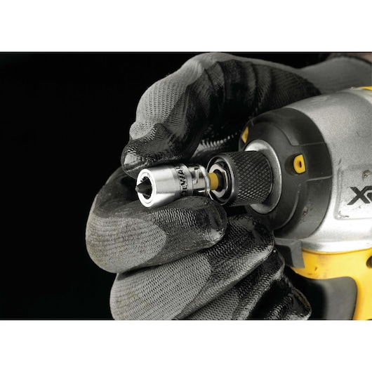 Gloved hand attaches DEWALT socket bit to power tool against a black background.