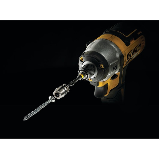 DEWALT drill with screwdriver bit and magnetic bit holder driving a screw in dark background.