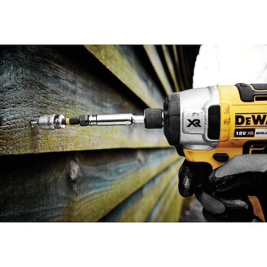 DEWALT drill with screwdriver bit driving a screw into wood siding.