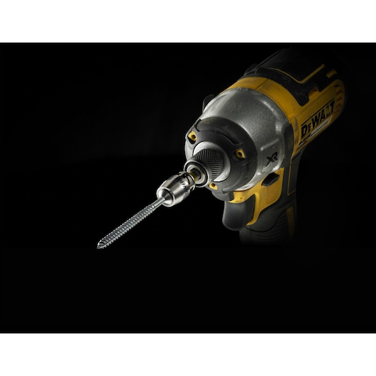 Close-up of a yellow DEWALT power drill with a metal drill bit, shown against a dark background.