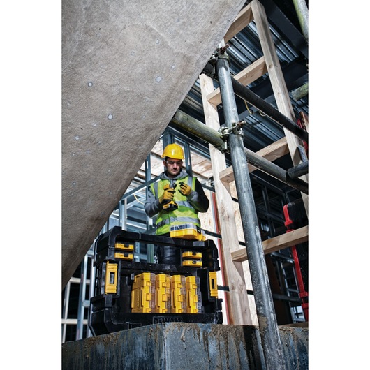 A DEWALT DT70716 tool organizer box placed on a block at a construction site, with various yellow tool compartments visible
