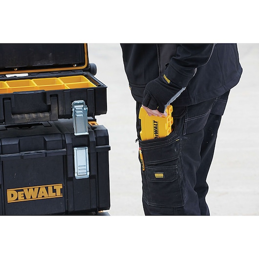 Person stores a DEWALT tool kit in pocket near a DEWALT toolbox with compartments, both black and yellow.
