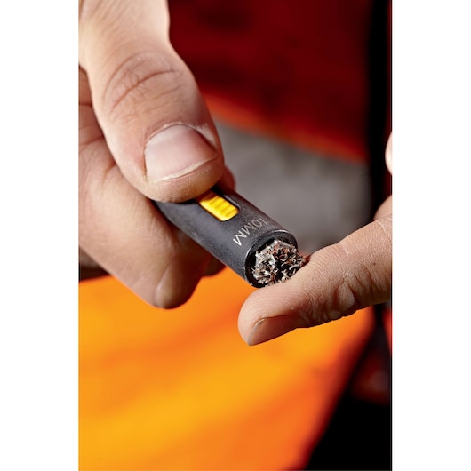 Close-up view of a hand holding a DEWALT tool with a 10mm wire brush tip, cleaning or preparing the surface of a finger.
