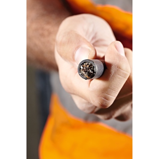 Close-up of a person holding a thick, multi-strand electrical cable with exposed copper wires at the end.
