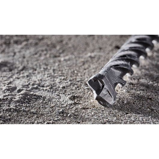 Close-up of a DEWALT DT8907 drill bit lying on rough concrete surface.