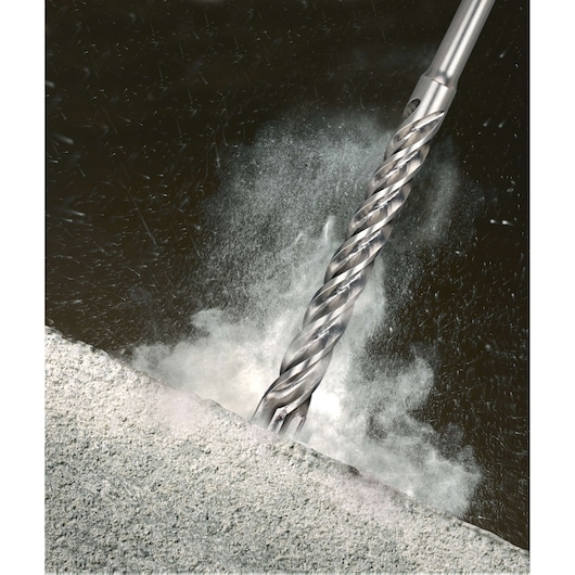 Close-up image of a metallic drill bit cutting into a concrete surface, causing dust and debris to disperse.