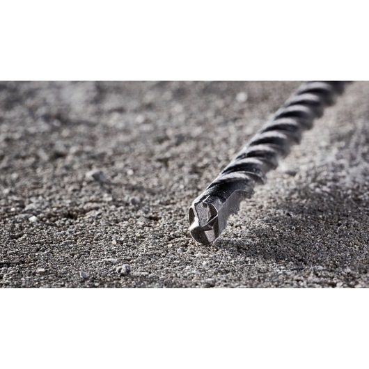 Close-up of a DEWALT DT8930 masonry drill bit lying on a rough concrete surface.