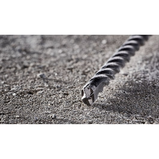 Close-up view of a DEWALT DT8932 masonry drill bit lying on a rough concrete surface.