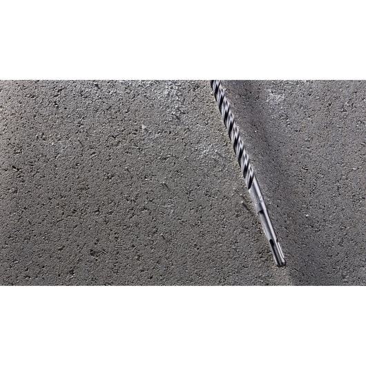 A DEWALT DT8937 masonry drill bit is shown inserted into a concrete wall.