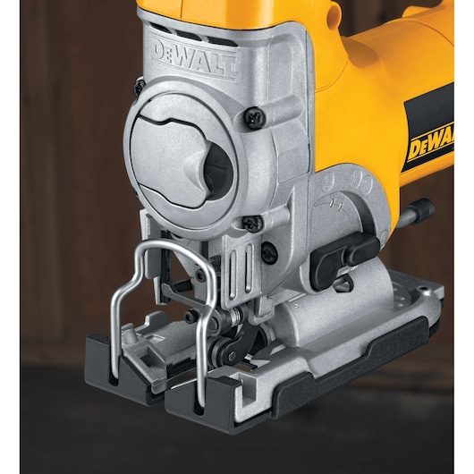 Close-up of a DEWALT jigsaw power tool, showing the metal blade guard, adjustment controls, and part of the yellow and black body.