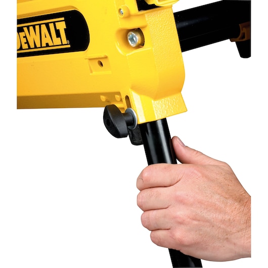 Hand adjusts the black leg of a yellow DEWALT tool, focusing on the locking knob mechanism.