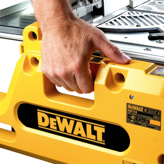 Hand holding handle of a yellow DEWALT DW743N tool with visible logo and label.