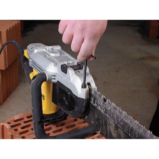 Hand uses a tool to adjust the DEWALT DWE398 saw on a brick surface.