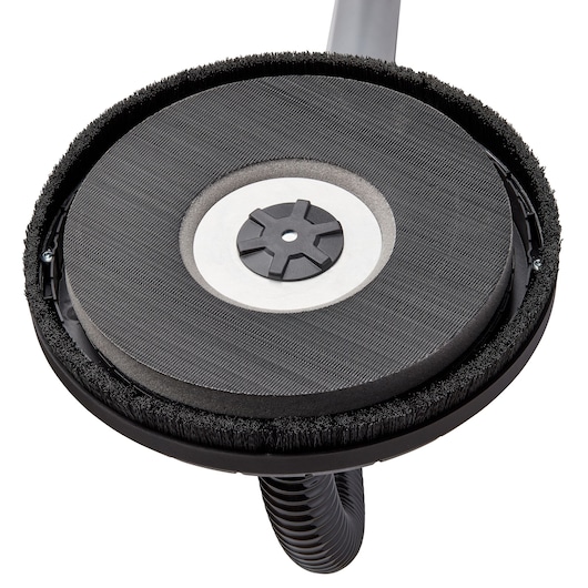 Close-up view of the sanding head of a DEWALT drywall sander, showing the circular sanding pad and brush edge attachment.