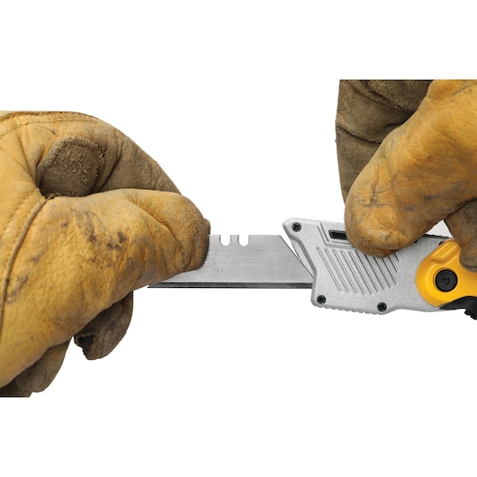 Gloved hands changing blade on a DEWALT utility knife against a white background.