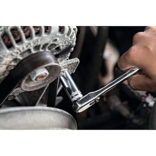 A close-up of a hand using a DEWALT ratchet wrench to tighten or loosen a bolt on a mechanical component, likely part of a