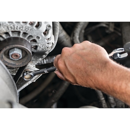 Hand using a DEWALT ratcheting wrench to tighten a bolt in a vehicle engine area.