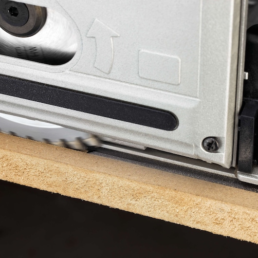 Close-up of a DEWALT track saw cutting through a piece of wood, showing the saw blade in action.