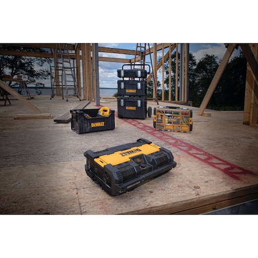 A group of DEWALT tool storage boxes, including a stackable black and yellow toolbox, open crate, and organizer, are