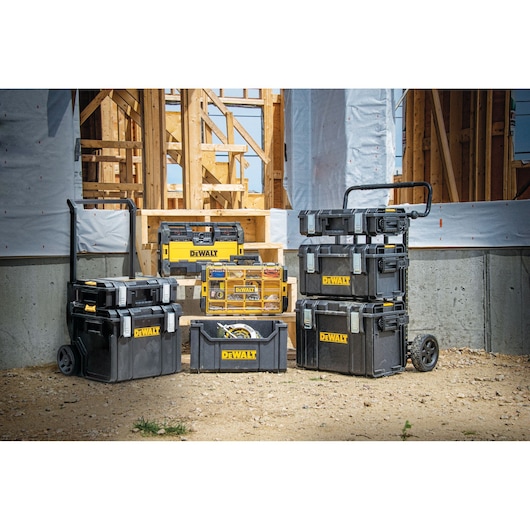 A collection of DEWALT storage boxes, toolboxes, and organizers with the yellow DEWALT logo are arranged outdoors at a