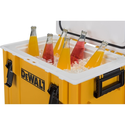 A yellow DEWALT cooler box with the lid open, containing ice and several glass bottles with colorful beverages inside.