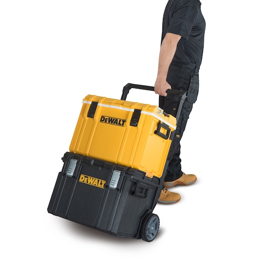 A person in workwear is pulling a DEWALT rolling toolbox with two stackable compartments, one yellow and one black, on wheels.